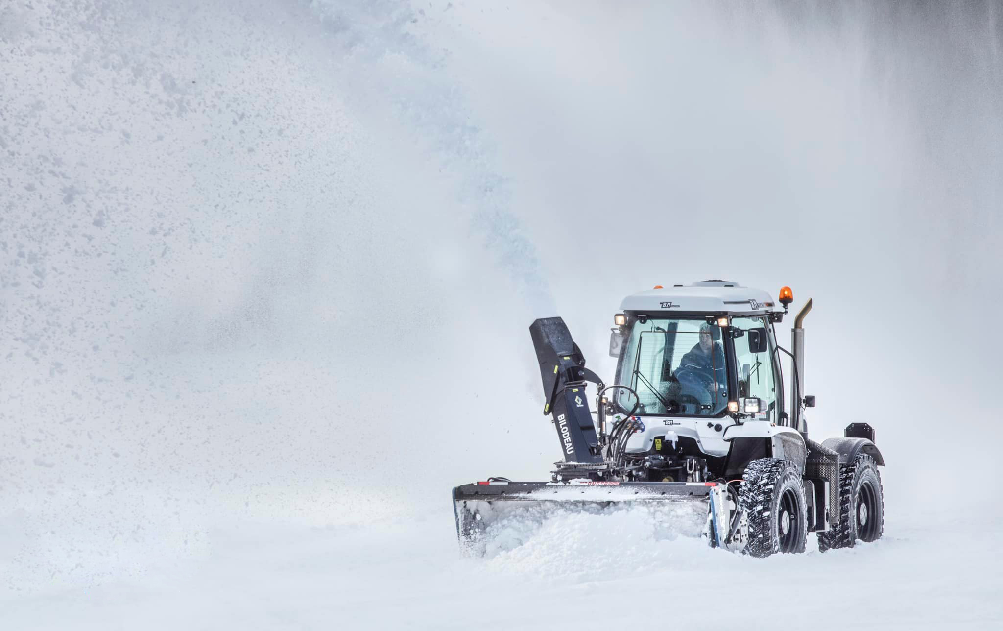Snowblower throwing an arc of snow across a driveway onto the lawn